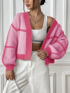 Detail of pink plaid knit cardigan showing chunky texture and ribbed cuffs on the model