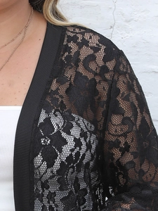 Gros plan d'un gilet en dentelle noire avec motifs floraux et bordure côtelée détaillée