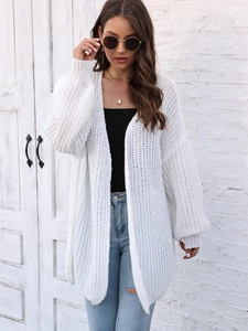 Detailed close-up of a white chunky knit cardigan featuring loose lantern sleeves and texture
