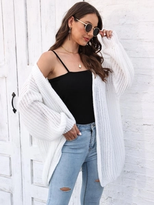 Close-up detail of white chunky knit texture on loose cardigan for women in outdoor light
