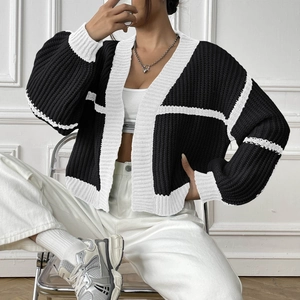 Detail view of heavy-knit cardigan showing contrast plaid pattern and ribbed edges