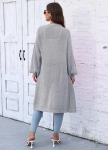 Vista posteriore esterna di un cardigan grigio lungo in maglia con maniche a lanterna
