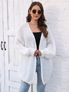 Detail of white chunky knit cardigan featuring hollow weave texture and loose-fit long sleeves