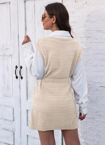 Detailed texture of beige knitted vest paired with a white long-sleeve shirt dress