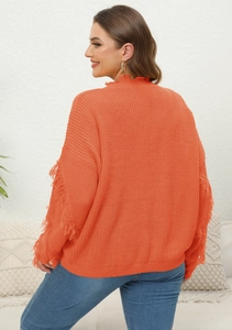 Detail of orange knitted sweater featuring fringe tassels on the back and dropped shoulders