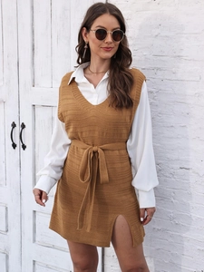Detail of camel knit vest dress with side slit and waist tie over white long sleeve shirt
