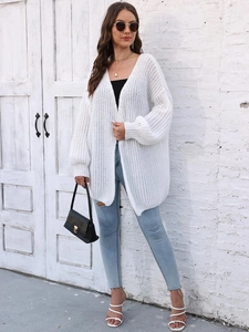 Close-up of white chunky knit cardigan texture with loose bishop sleeves and ribbed cuffs