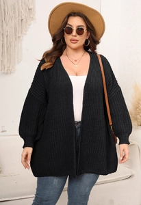 Detail view of women's chunky knit black cardigan in a cozy lifestyle indoor setting