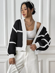 Detail of chunky knit texture and contrast black and white plaid pattern on cardigan