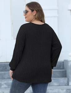 Detail view of black ribbed knit plus-size long sleeve top with loose fit back style