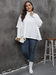Detail of loose-fit white knit sweater featuring a chic high collar and cape-style batwing sleeves