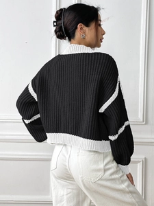 Detail of knit sweater back view featuring contrasting black and white striped cuffs