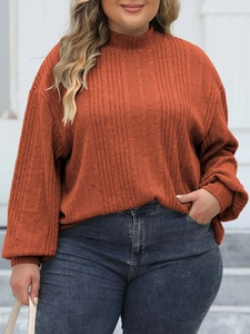 Detail of burnt orange mock neck ribbed knit top showing texture and loose fit