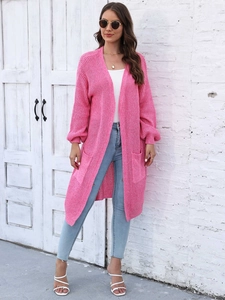 Dettaglio di un lungo cardigan in maglia rosa acceso con grandi tasche laterali