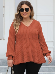 Close-up of rust brown ribbed knit peplum top with V-neck and puff sleeves for women