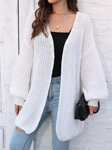 Close-up of white chunky knit cardigan with lantern sleeves and rib-knit cuffs on a model