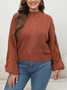 Detail of chunky knit brick red sweater featuring textured cable patterns and mock neck