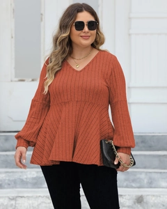 Detail view of plus size brick red V-neck top with ribbed texture and flared hem