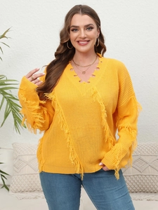 Detail of yellow V-neck knitted sweater featuring bohemian fringe and tassel hem accents