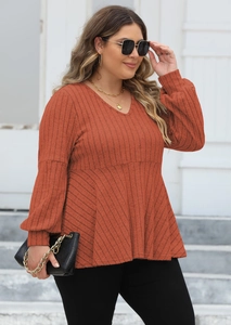 Detail of V-neck ribbed knit top with puff sleeves and peplum waist in terracotta color