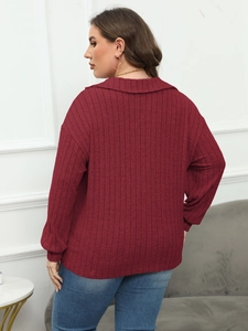 Detail of the wine red ribbed knit polo top featuring a wide collar and fitted cuffs