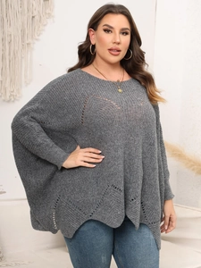 Detail eines grauen Plus-Size Strickponchos mit hohlen Mustern und wellenförmigem Saum
