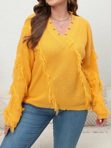 Detailed knit texture of a bright yellow V-neck sweater with long fringe and tassels