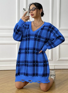 Detail of ripped hem on a blue and black checkered V-neck knit oversized sweater dress