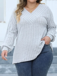 Detail of grey ribbed knit V-neck top with cross-over design and long sleeves