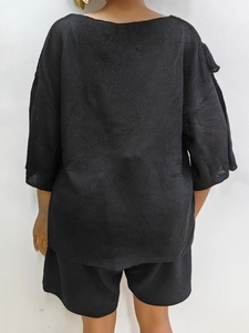 Rear view of loose black knit top with half sleeves and textured ruffle stitching details