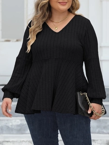 Detailed close-up of V-neckline and ribbed knit texture on a black long sleeve peplum top