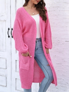 Dettaglio della trama a maglia grossa e grandi tasche sul cardigan rosa