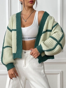 Detail of green and beige patchwork knit cardigan showing ribbed cuffs and texture