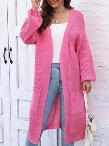 Dettaglio del cardigan in maglia rosa acceso con trama spessa e ampie tasche laterali