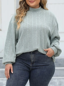 Detail of sage green mock neck ribbed knit long sleeve top paired with blue jeans