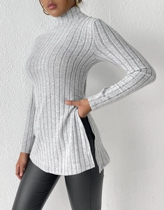 Detail view of light grey ribbed turtleneck sweater featuring elegant side slits on the hem
