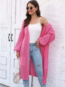 Dettaglio del cardigan lungo in maglia rosa acceso con grandi tasche e trama fitta