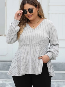 Close-up of light grey ribbed V-neck tunic top with puff sleeves and peplum hem