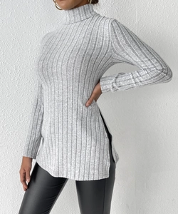 Detail of grey turtleneck sweater featuring ribbed texture and stylish high side slits