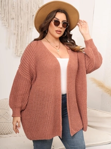 Close-up of chunky knit texture and lantern sleeves on a brick red open cardigan