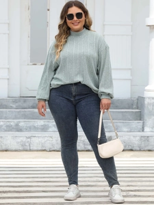Detail of light green ribbed knit long sleeve top with mock neck and textured fabric