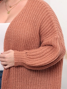 Detail of rust orange chunky knit cardigan showing thick textured yarn and ribbed cuffs