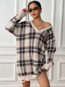 Close-up of V-neck plaid knit sweater dress featuring stylish distressed hem and cuffs