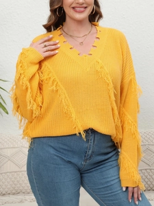 Detail of yellow V-neck oversized knitted sweater with shredded fringe and distressed texture