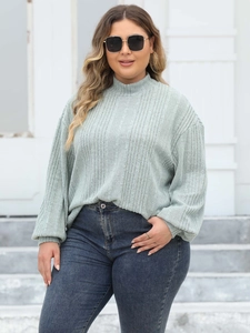 Detail of sage green ribbed knit top featuring a mock neck and stylish puff sleeves