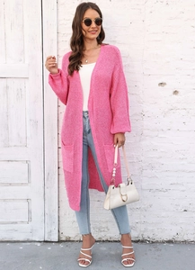 Dettaglio del cardigan in maglia rosa con ampie tasche laterali e polsini a coste sulla modella