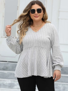 Detail of light grey V-neck babydoll top featuring textured rib-knit fabric and ruffle hem