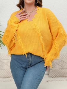 Detail of yellow knit sweater featuring V-neckline distress and long bohemian fringe accents