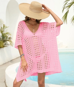Detail of pink crochet beach cover-up featuring intricate hollow knit patterns and V-neck