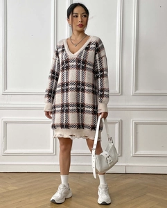 Close-up of distressed hem and fringe detail on a plaid knit V-neck sweater dress